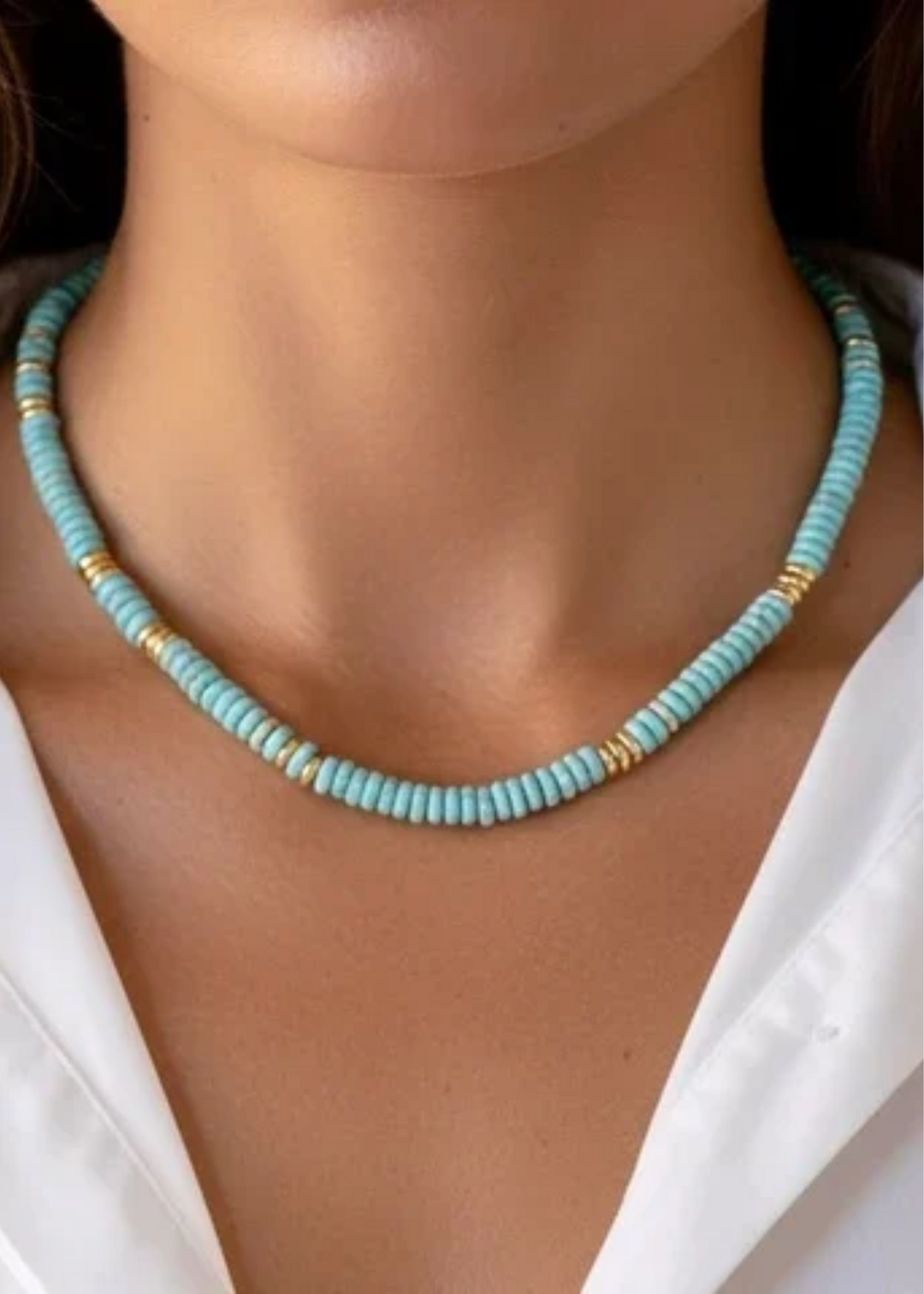 A woman wearing a light blue beaded necklace. 