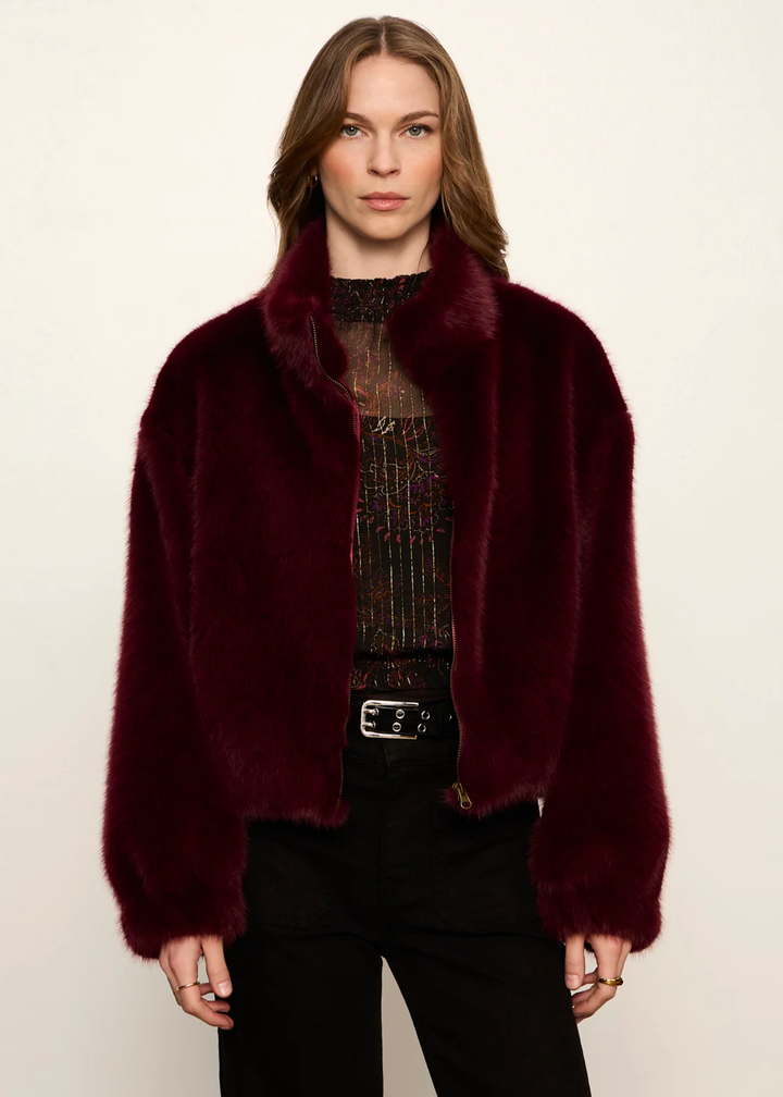 A woman wearing a maroon fur jacket.