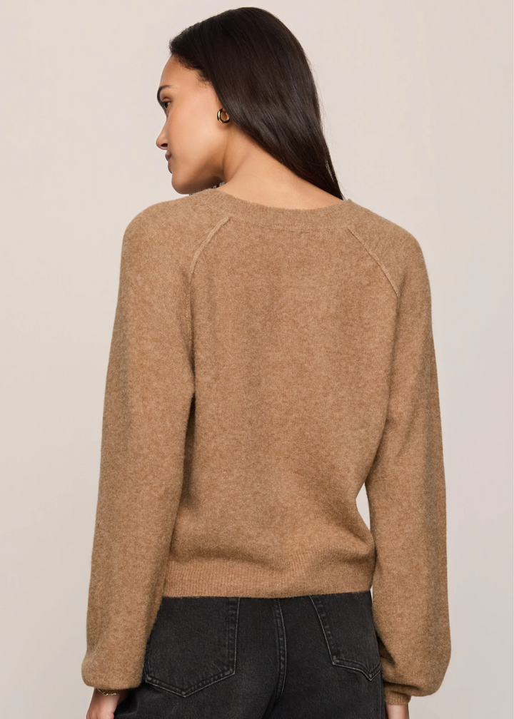 Woman wearing a brown sweater and black jeans and turned around.