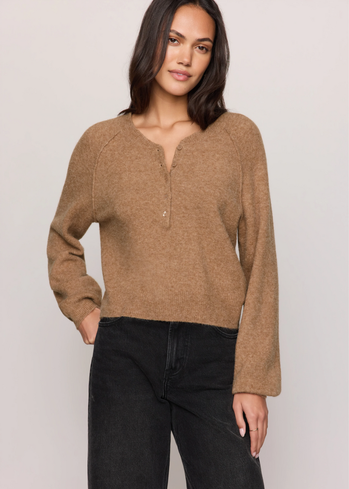 Woman wearing a brown sweater and black jeans.