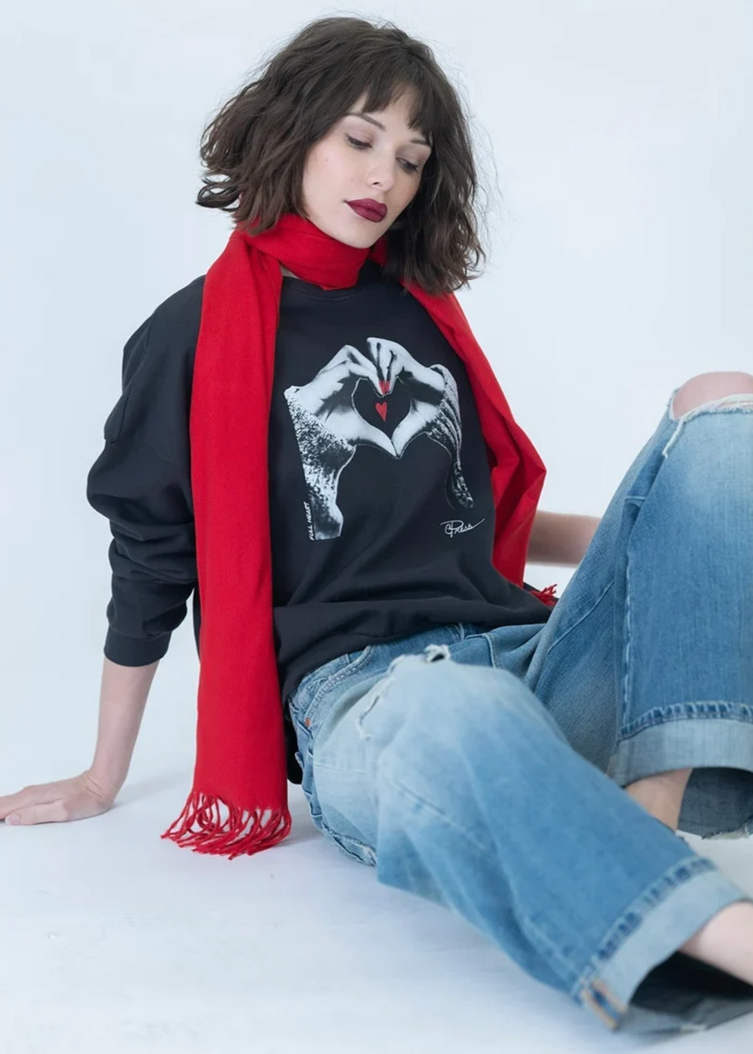 Woman wearing a grey sweatshirt with heart hands on it.