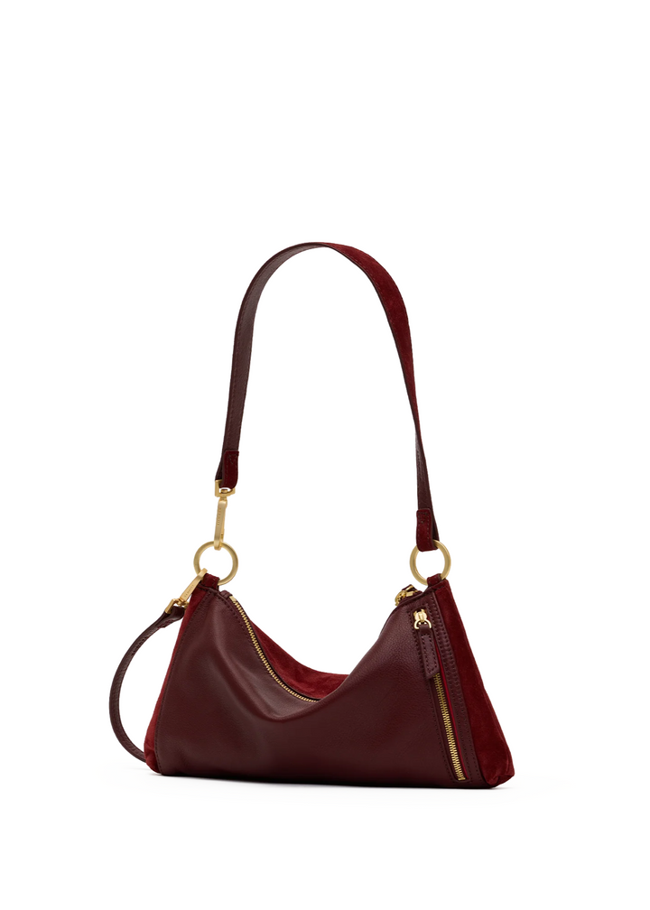 A burgundy leather shoulder bag with gold-tone hardware, featuring a crescent-shaped body, a long shoulder strap, and a zippered top closure, shown on a plain white background.