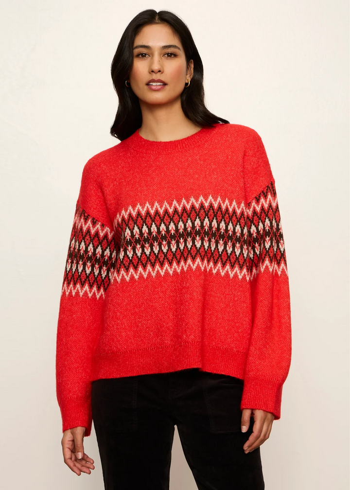 Woman wearing a red-hot argyle sweater with black pants.