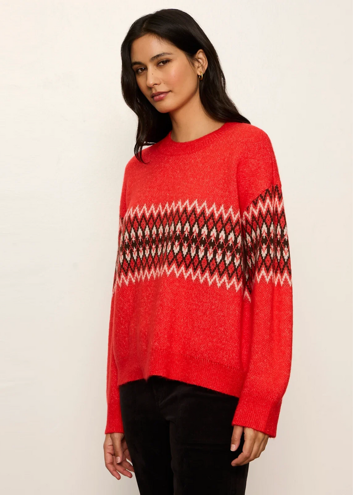 Woman wearing a red-hot argyle sweater with black pants.