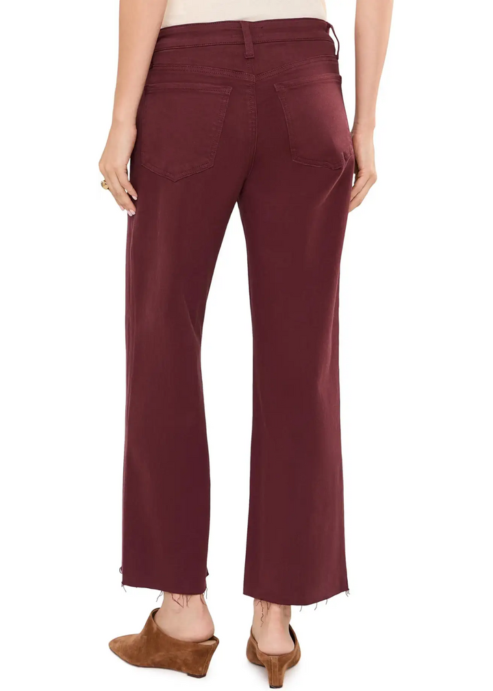 Rear view of a model wearing burgundy cropped flare jeans with a frayed hem and brown suede mule heels, against a plain white background.