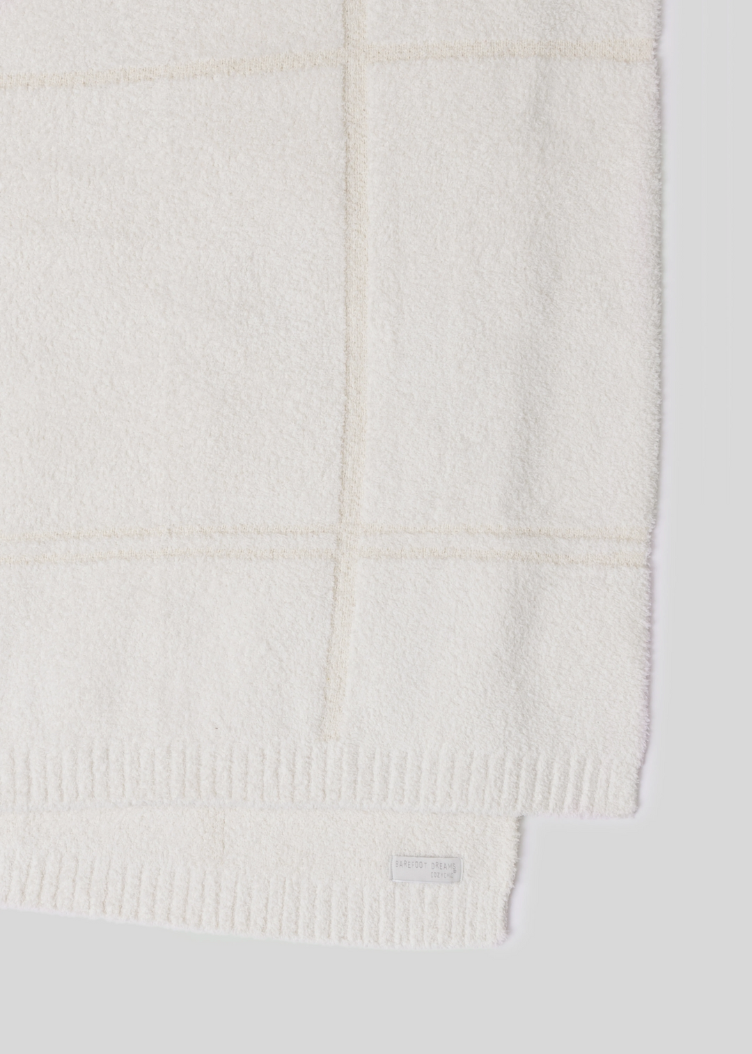 Cream colored plaid blanket laying on a white background