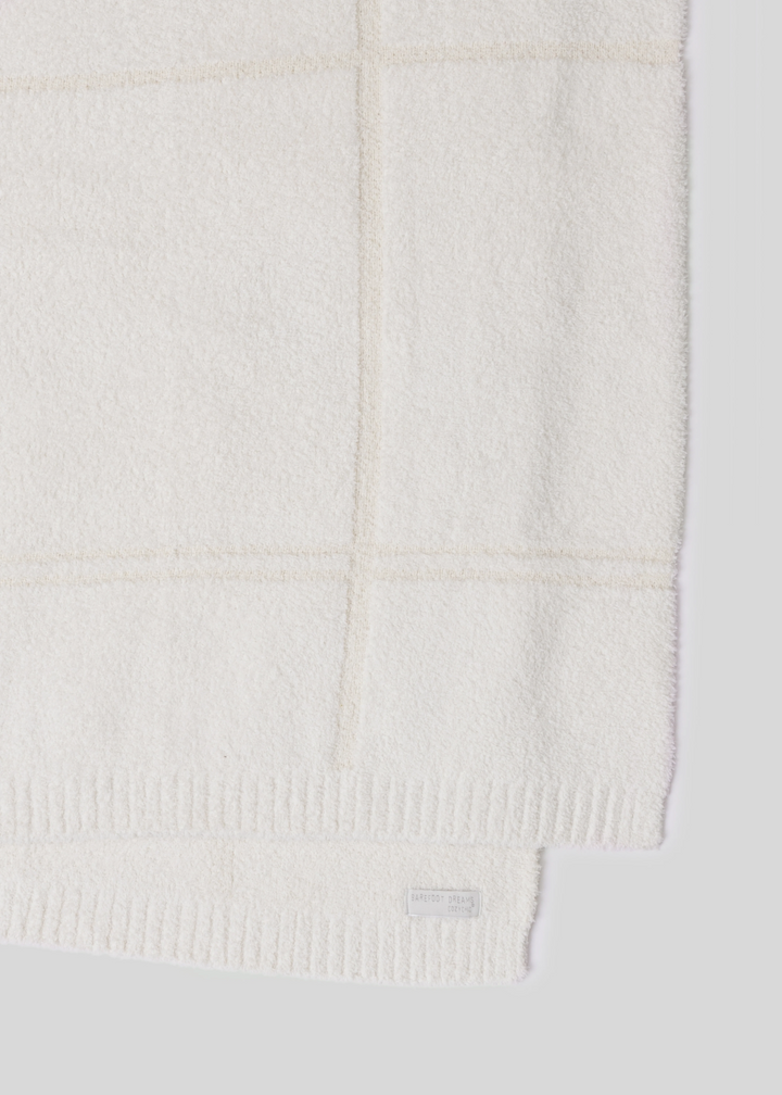 Cream colored plaid blanket laying on a white background