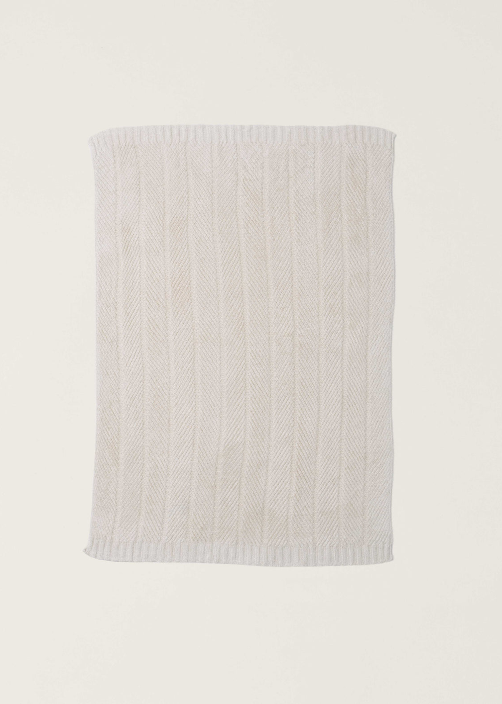 Cream blanket with a herringbone pattern laid on a white background