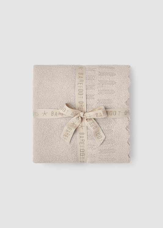 Cream blanket folded and tied with a cream ribbon sitting on a grey background