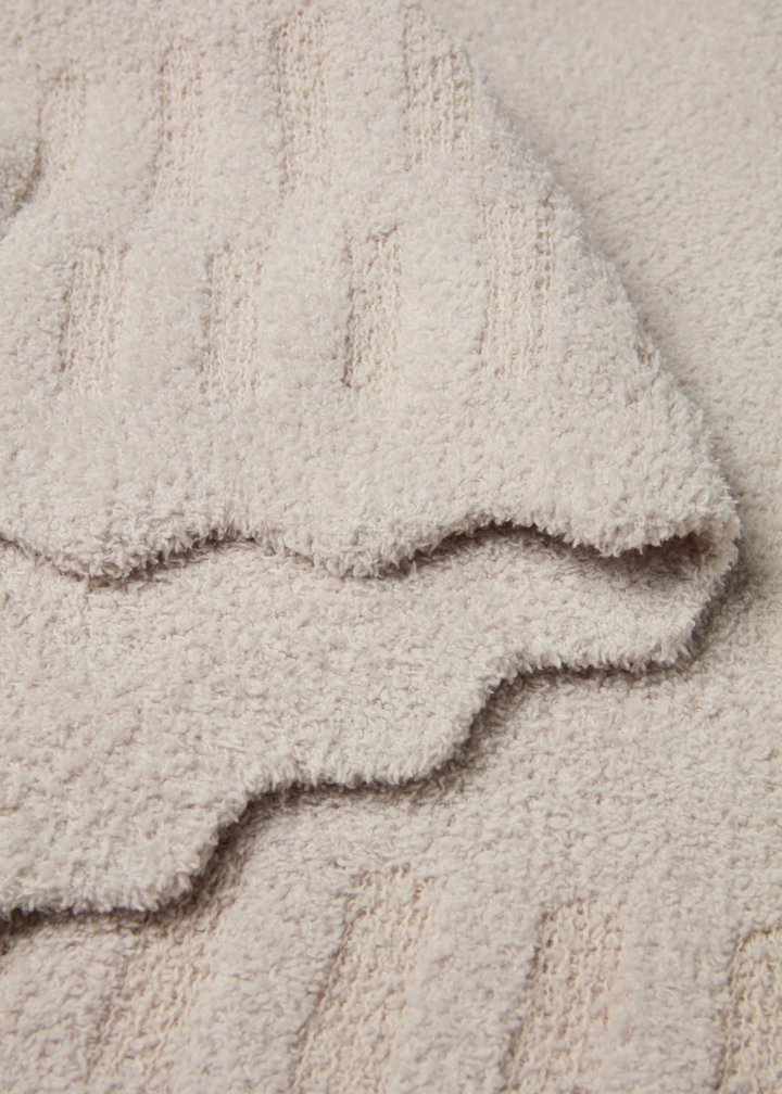 Cream blanket with scalloped edges laying folded
