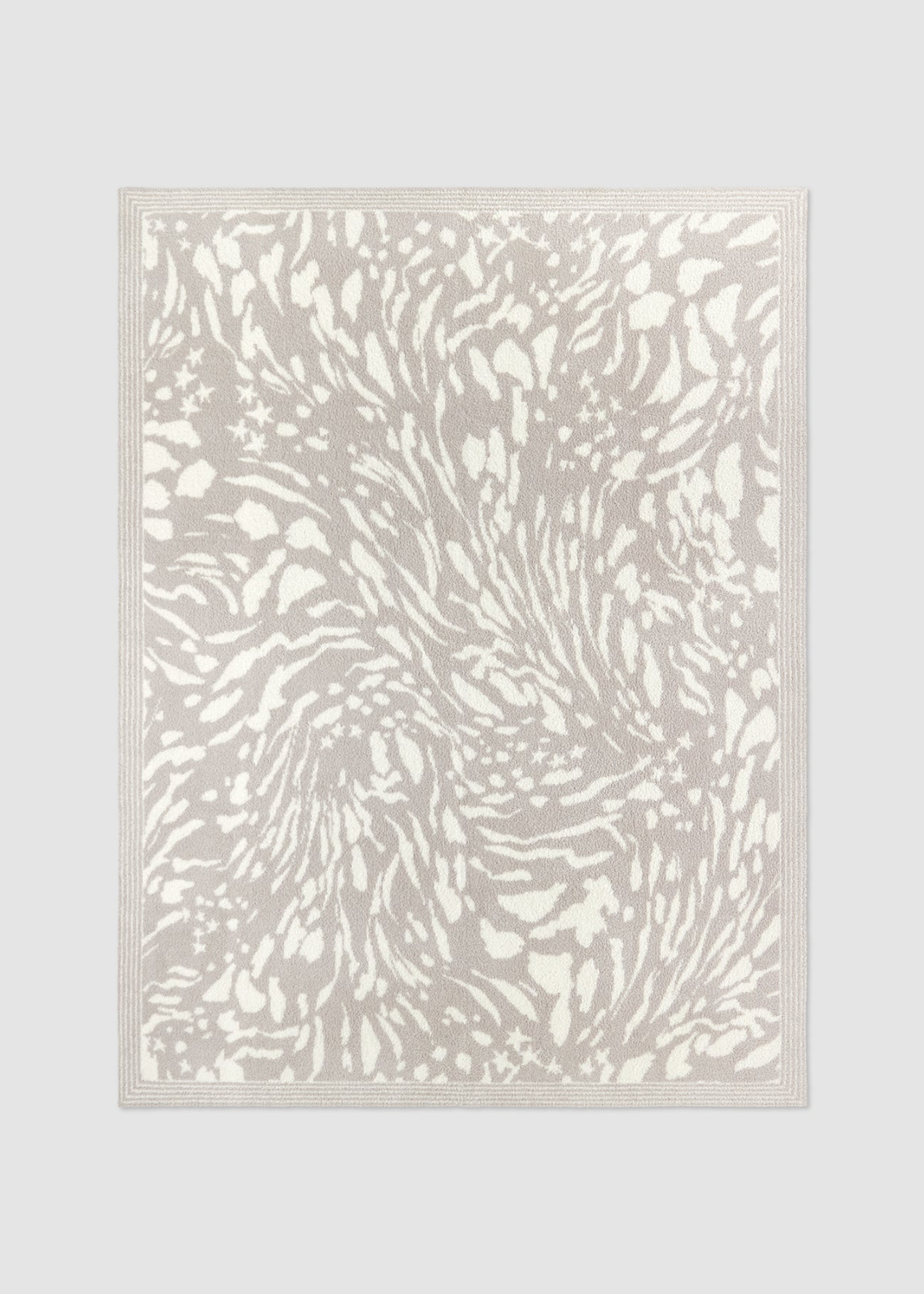 Grey and cream animal print blanket laying on a grey background
