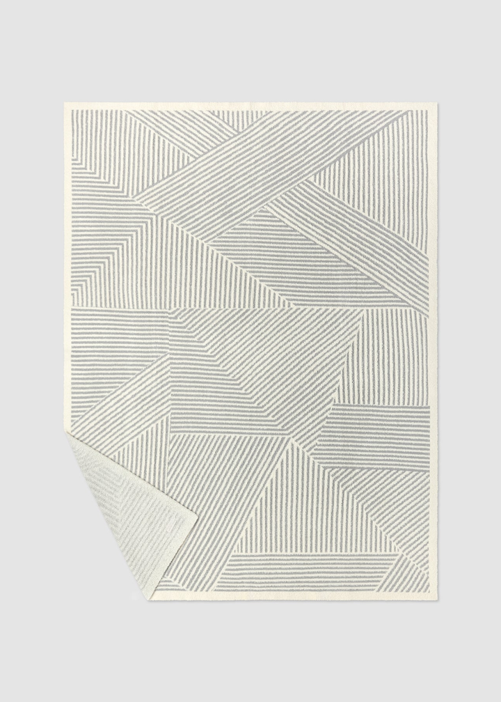 Grey and white striped blanket on a grey background with a corner folded