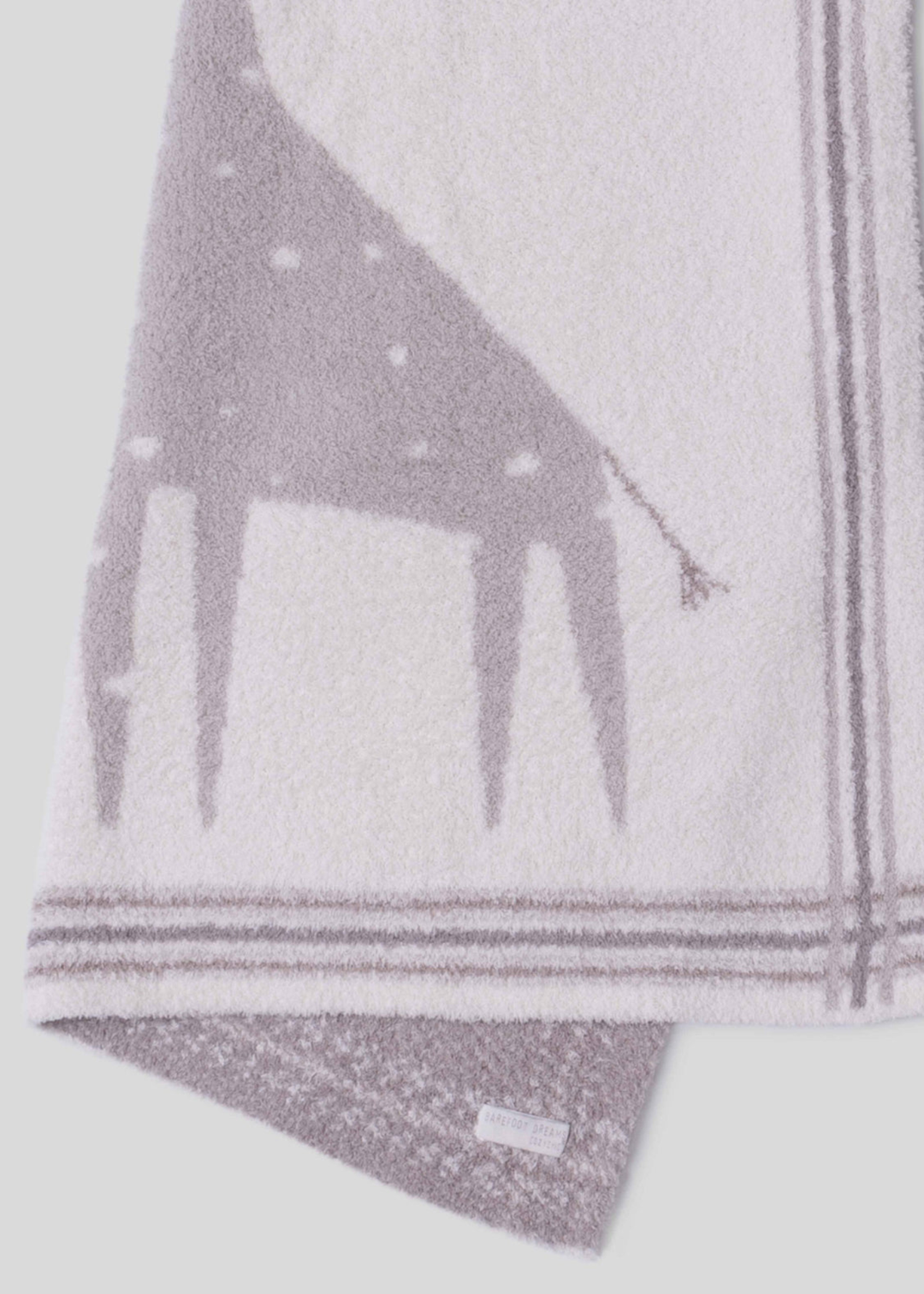 Close up of a pink and cream blanket with a giraffe graphic and a striped border folded in half on a white background