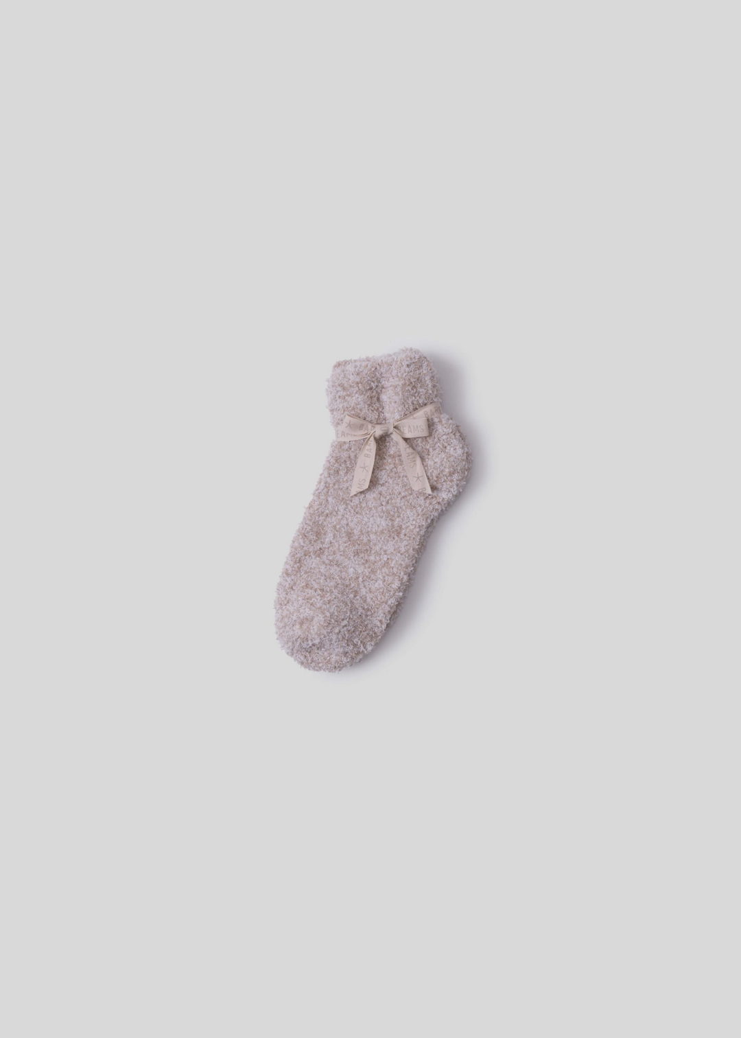 Tan socks tied with a tan bow laying on a white background