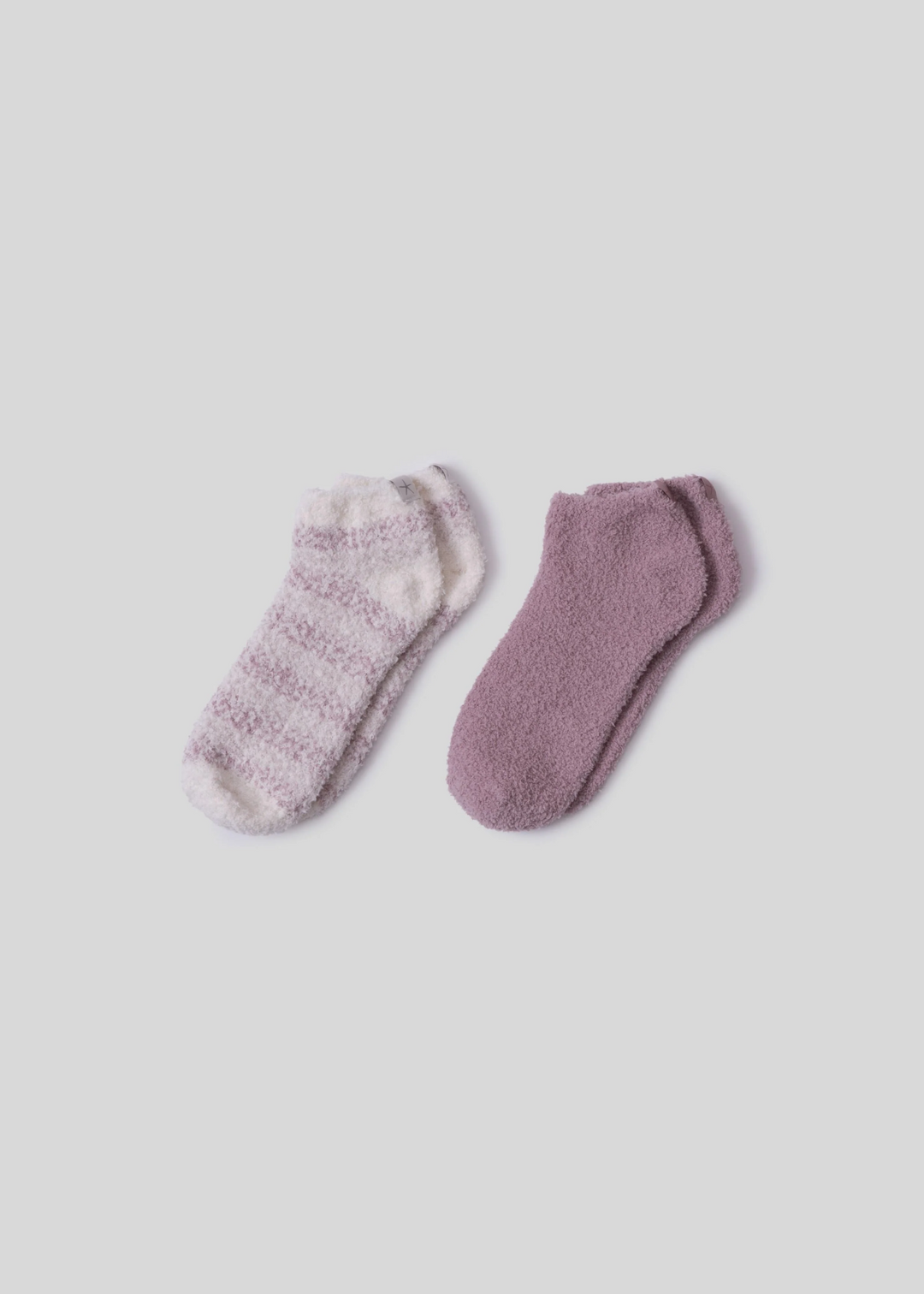 A pair of pink and white striped socks laying beside a pair of pink socks on a white background