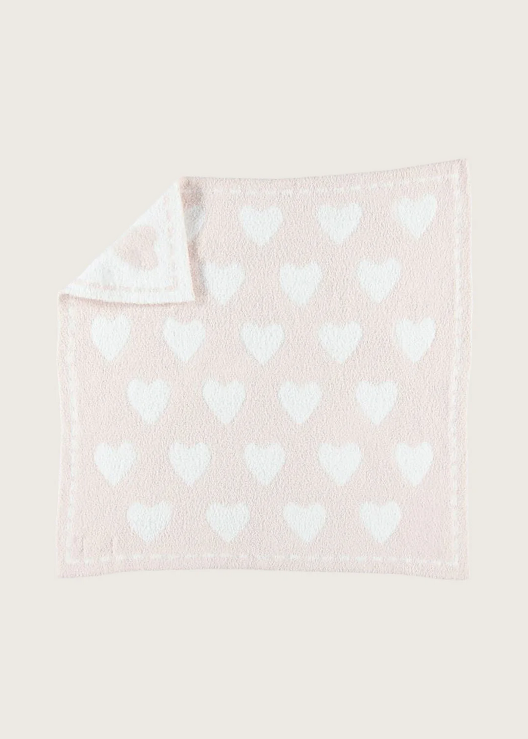 A reversible pink blanket with white hearts on a white background