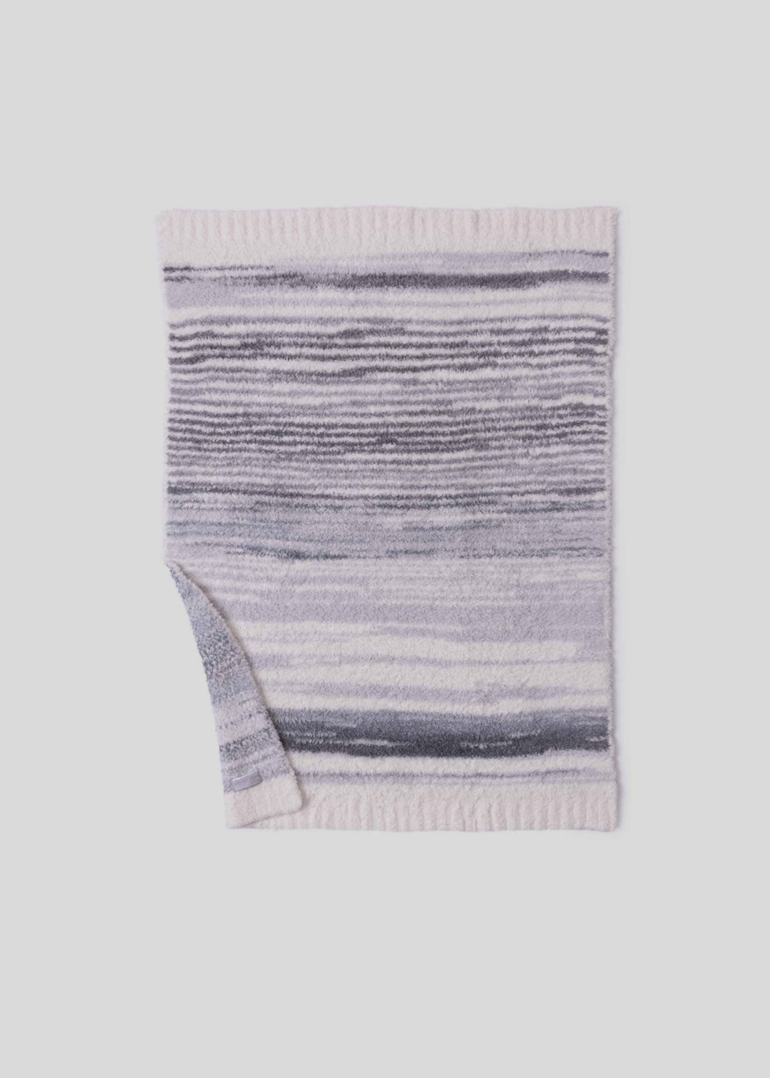 Blue, grey, and cream striped blanket laying on a white background with a corner folded