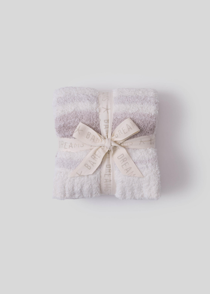 Pink and cream striped blanket folded and tied with a cream bow on a white background