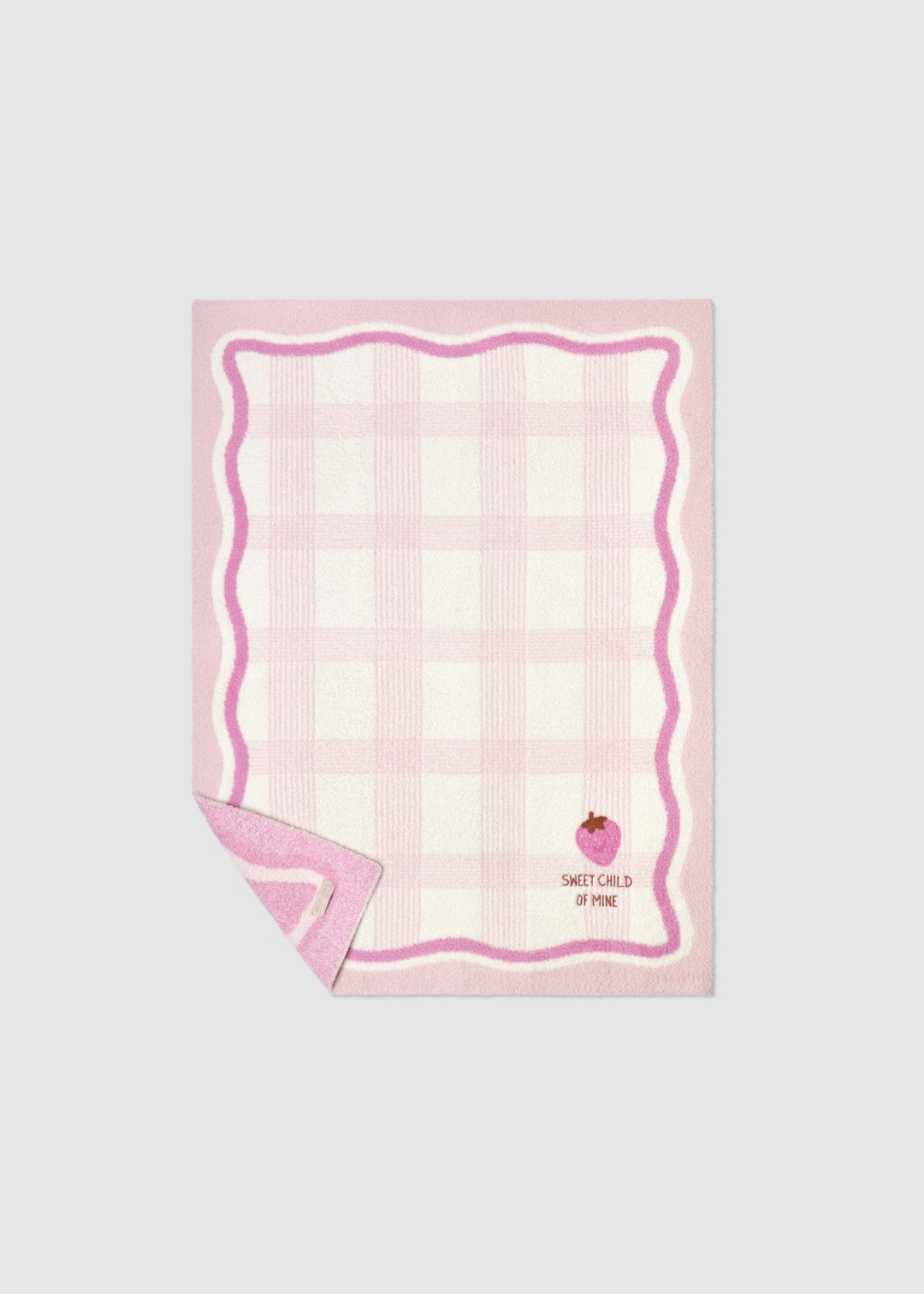 Pink baby blanket with a plaid pattern and an embroidered strawberry graphic and a corner folded up