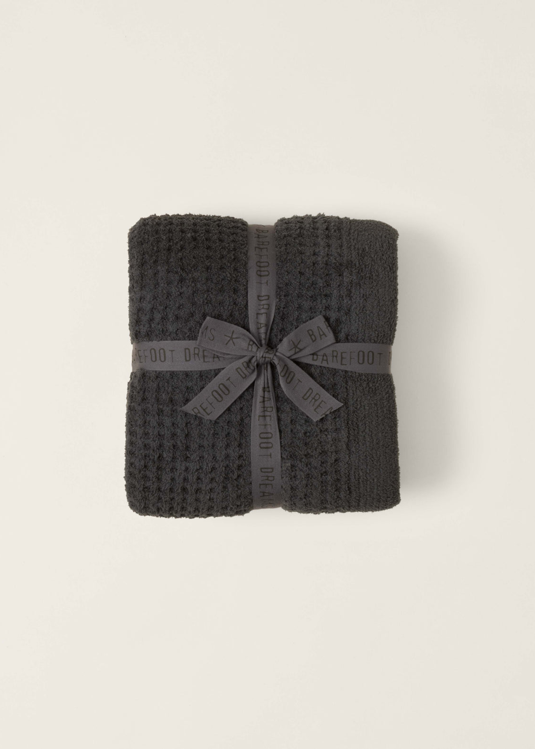 Dark grey waffle knit blanket folded with a grey bow on a white background