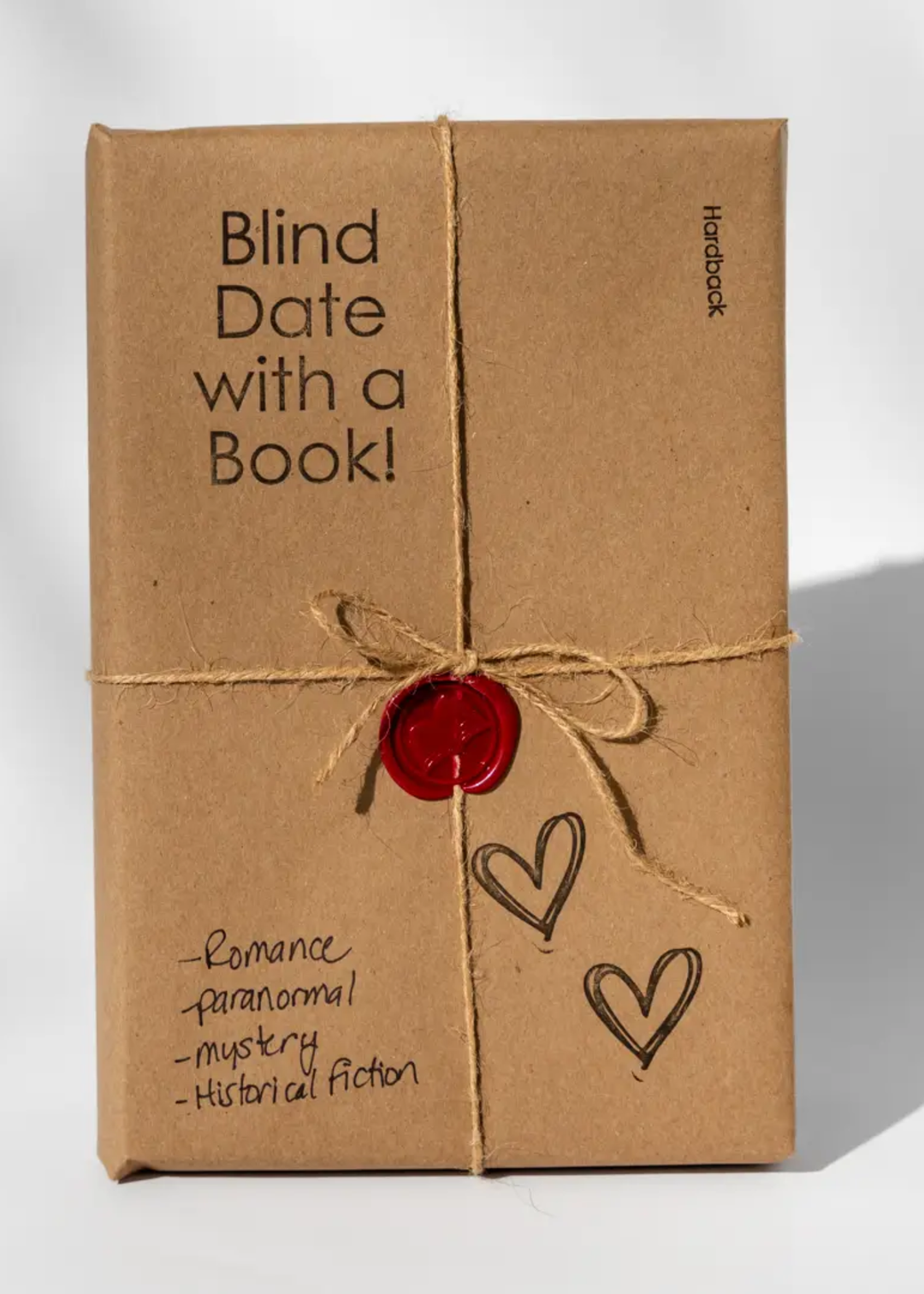 Book wrapped in brown paper with a bakers twine bow and a red wax seal