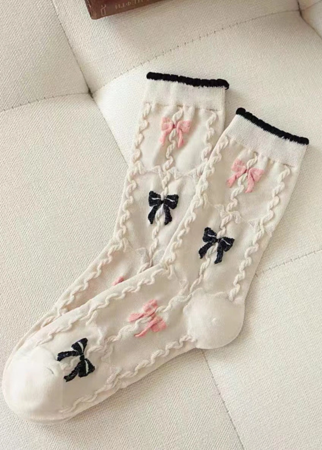 ivory knit socks with textured details and black and pink bow with black trim