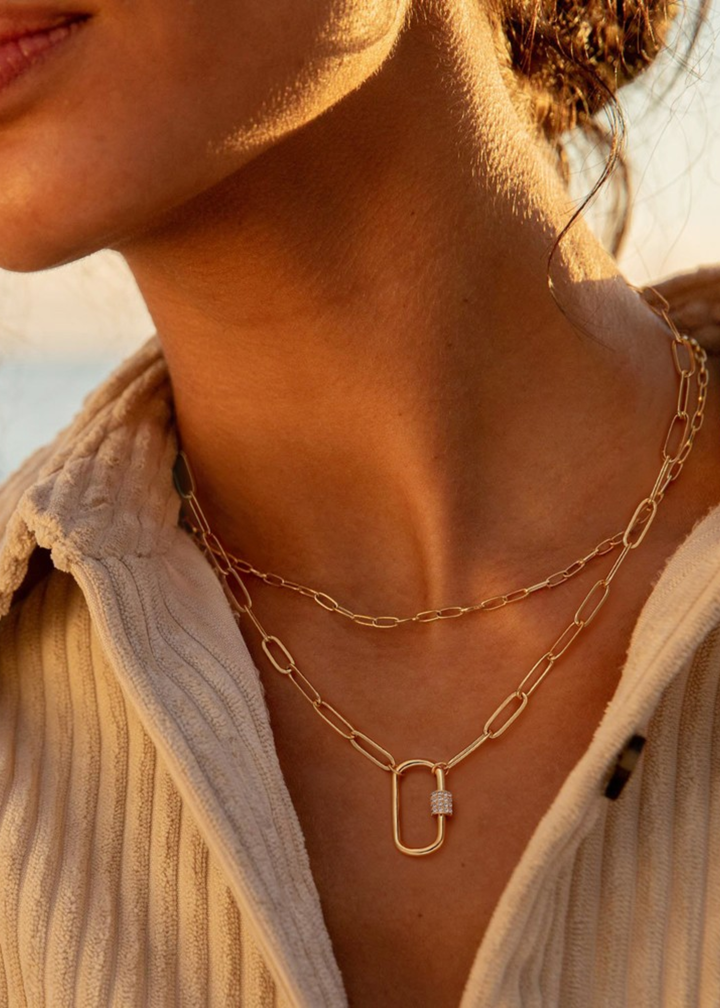 Woman wearing a gold chain necklace with a gold carabiner clasp