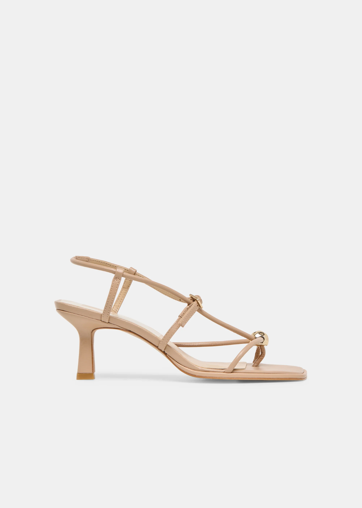 Side view of tan strappy heels with a gold button against a white background
