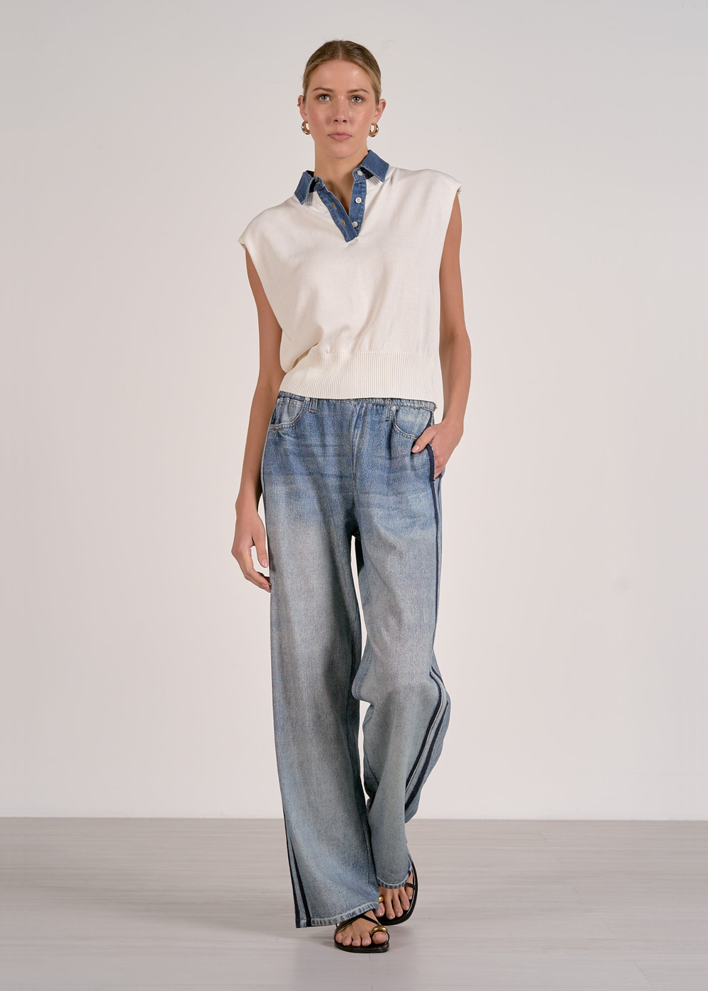 Woman with hand in pocket wearing a white knit top with jeans 