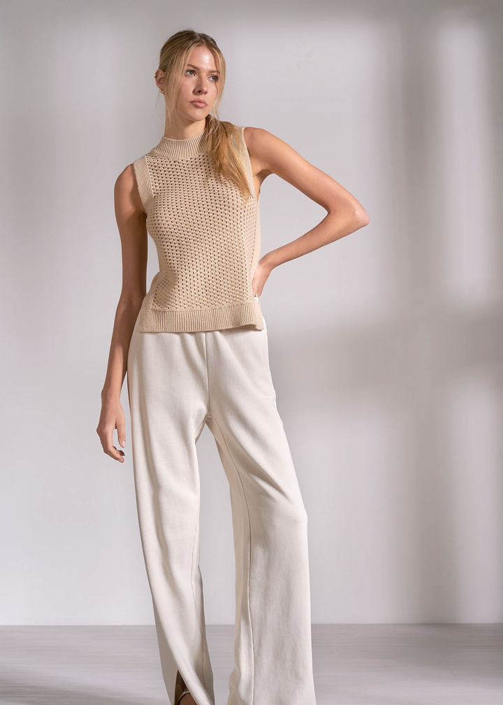 Woman wearing a tan knit tank top with cream pants