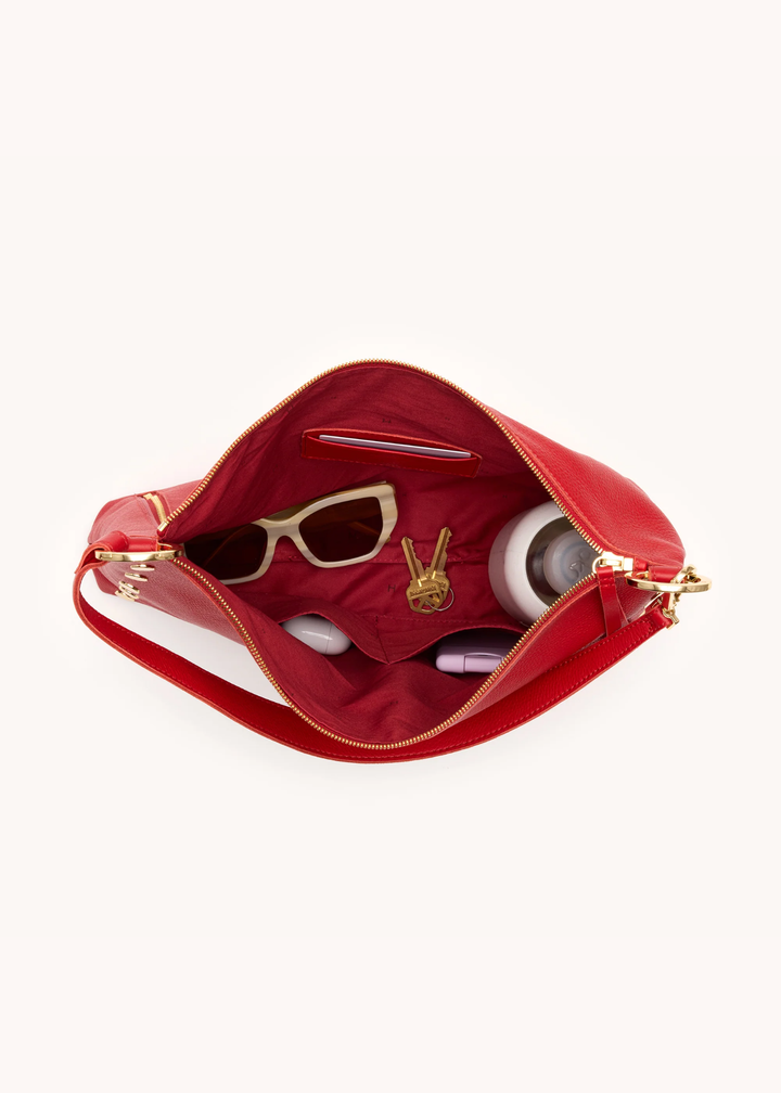 Red leather purse with gold hardware open with things inside