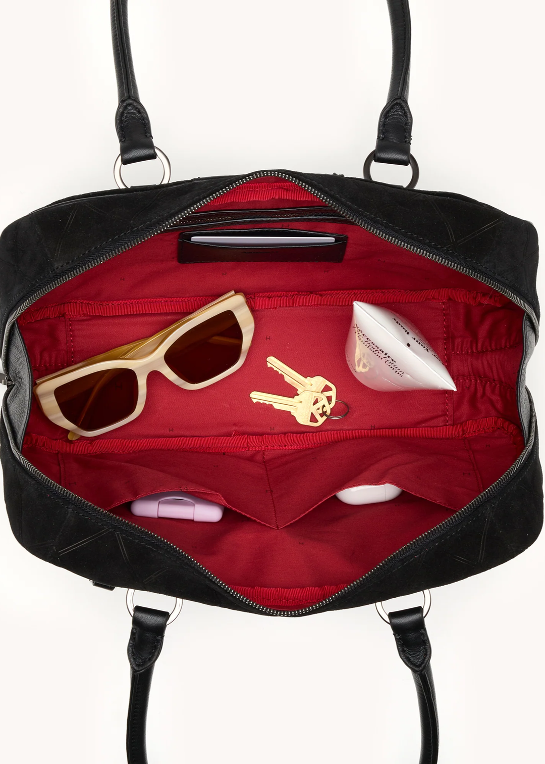 Black suede purse with red interior sittin open on a white background