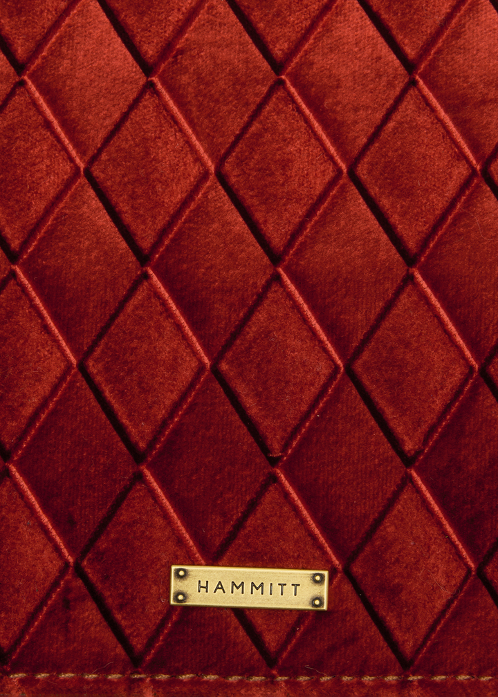 Close up of a red velvet pattern with a gold "HAMMITT" logo