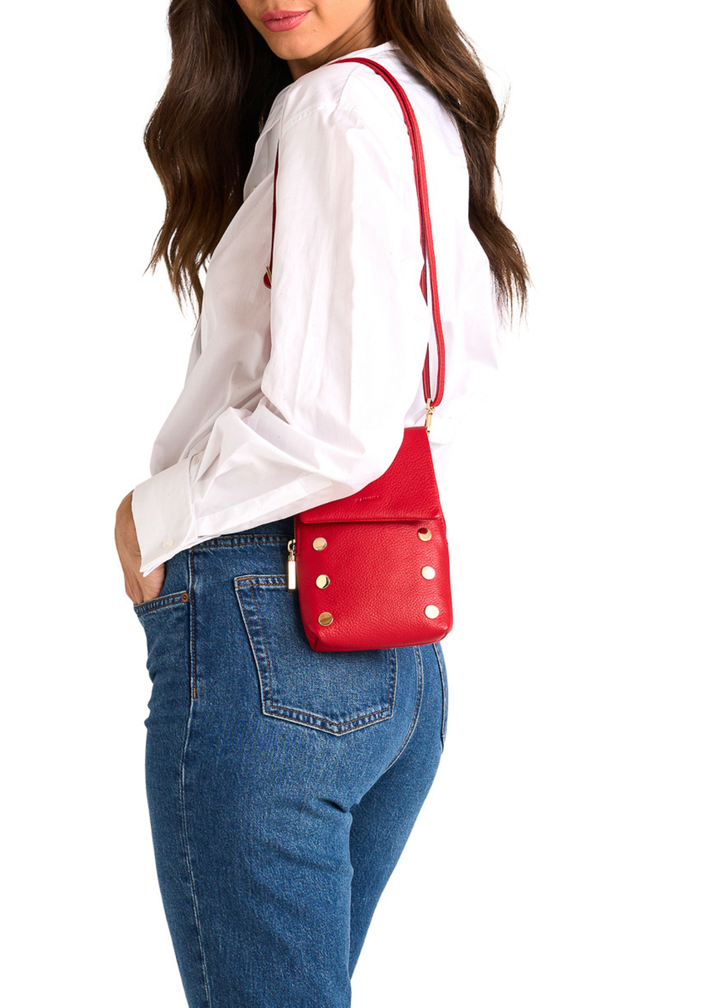 Woman with a red leather purse with gold accents on her shoulder