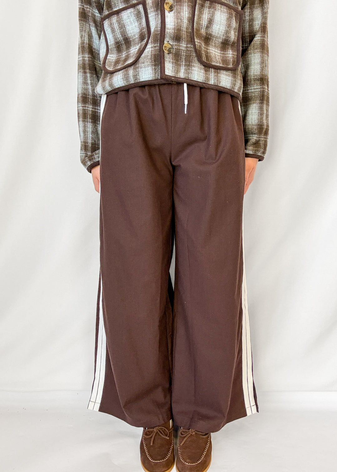 Woman wearing brown wide leg pants with white stripe down the side