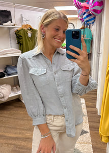 light blue button-down collared top with 3/4 puff sleeves and two chest pockets