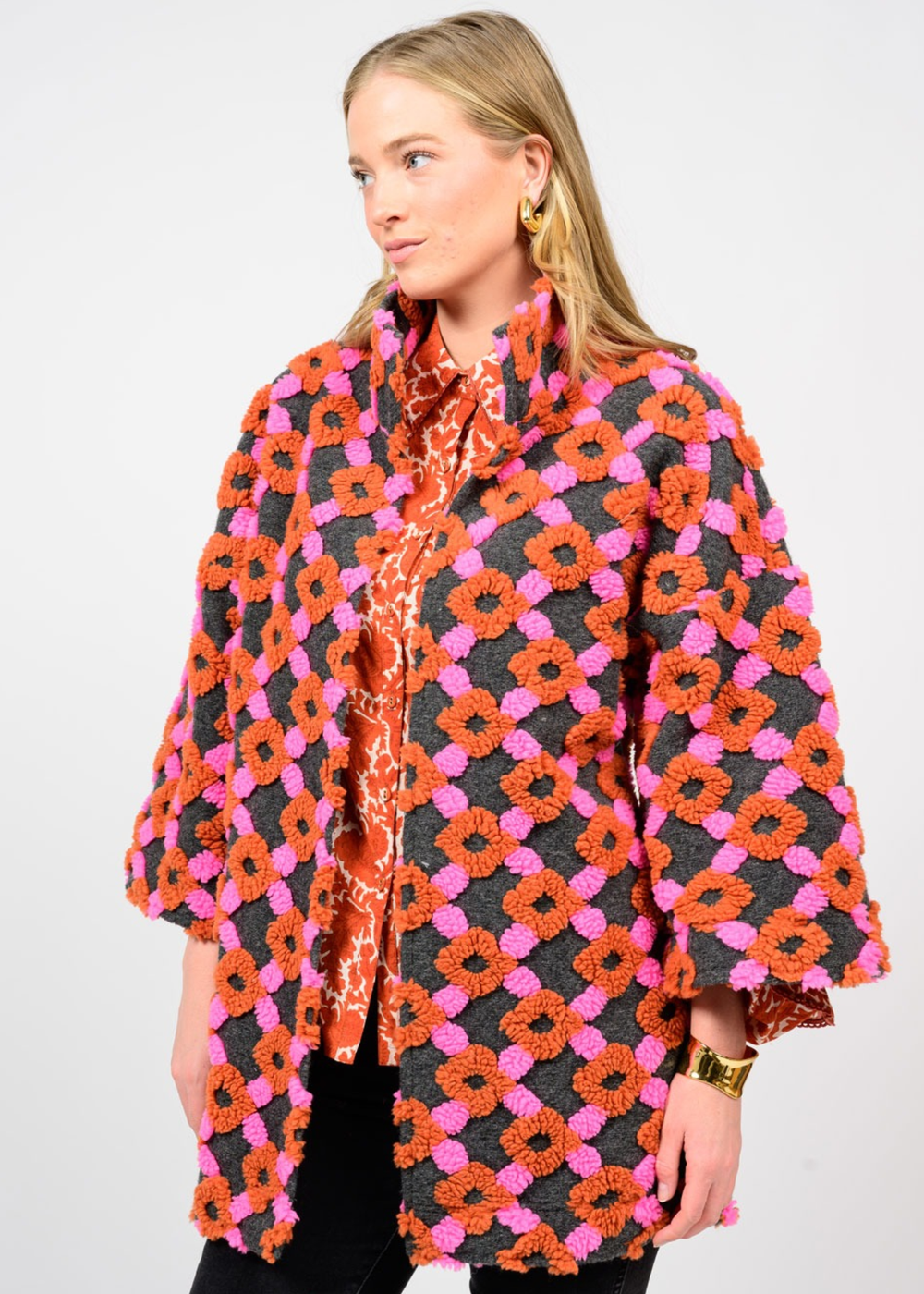 Woman turned to the side wearing a pink, orange, and grey patterned coat