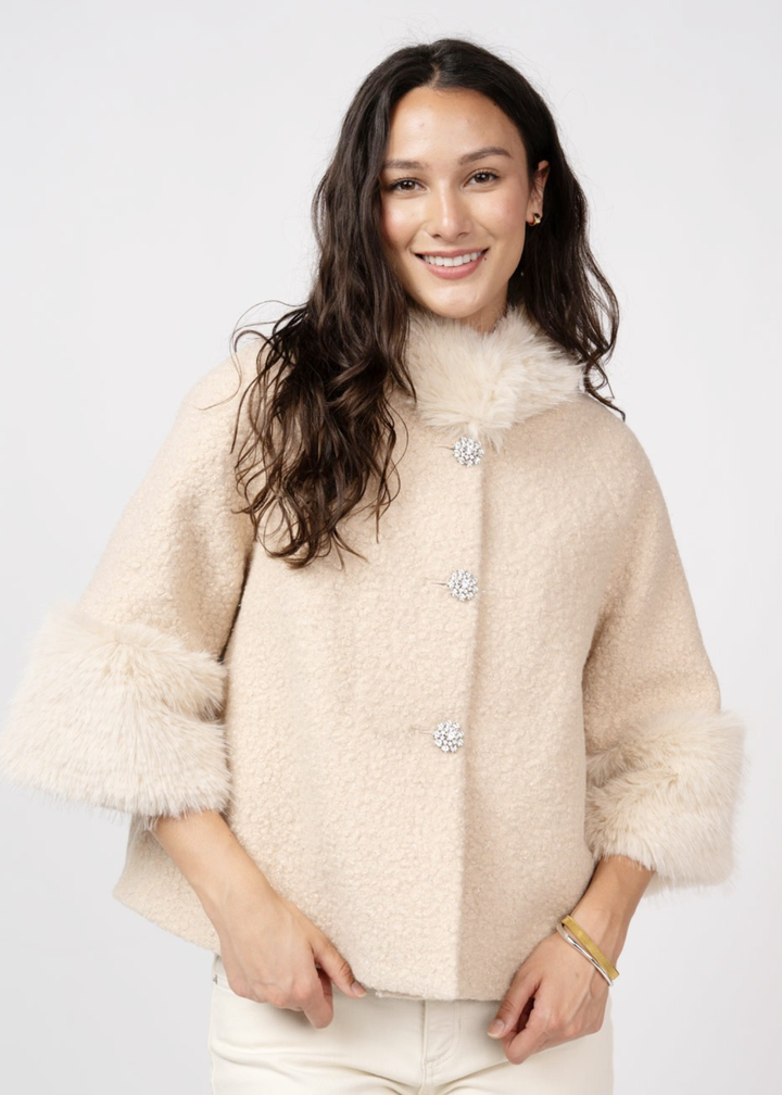 Woman wearing an ivory coat against a white background