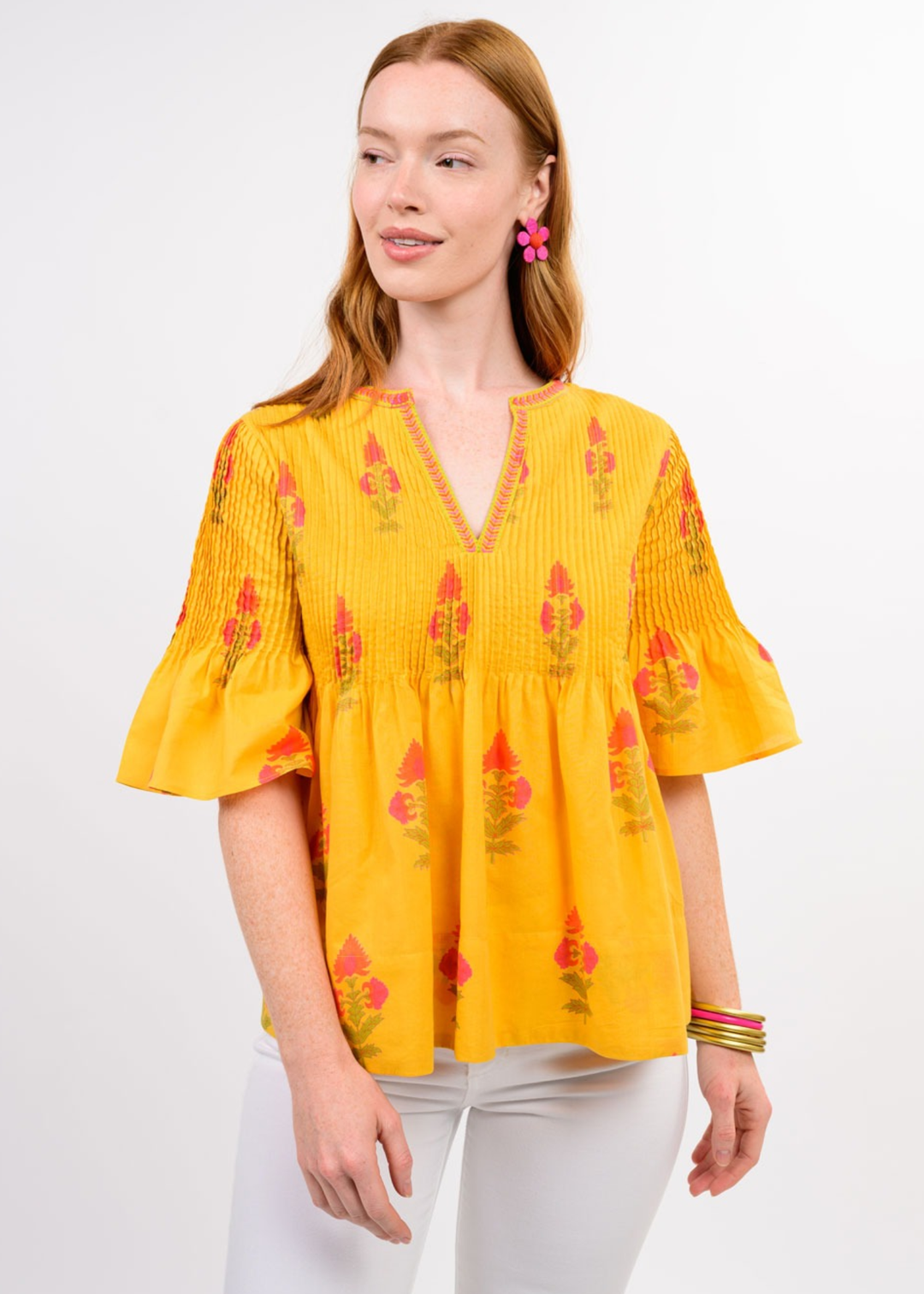 Woman wearing a yellow v-neck top with a floral print and white jeans