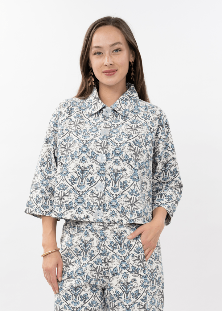 Woman wearing a blue and white floral button down top with 3/4 length sleeves and matching pants