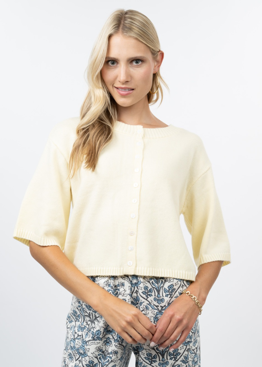 Woman wearing a light yellow short sleeve cardigan with floral pants