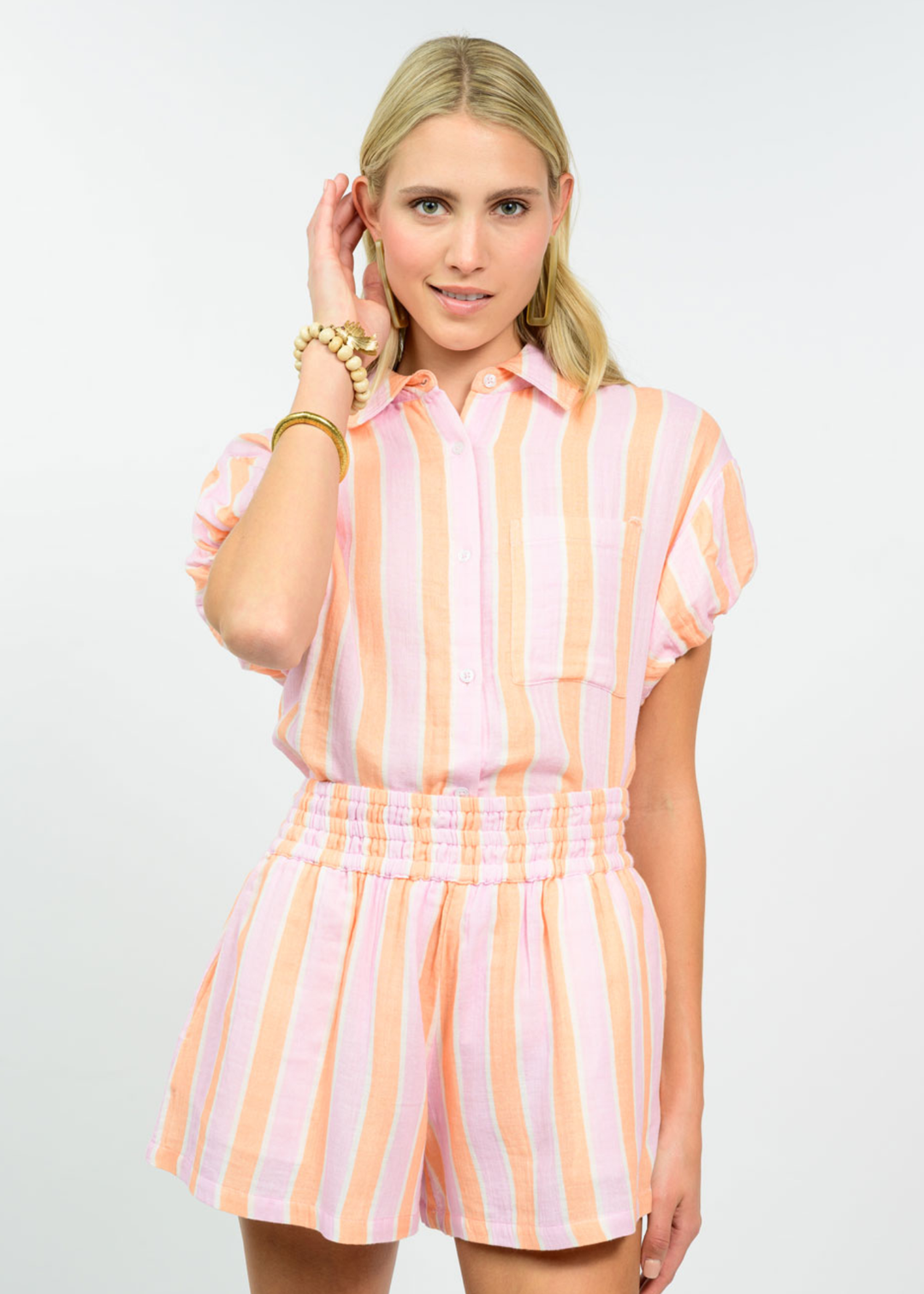 Woman wearing a tangerine striped collared button down with matching shorts