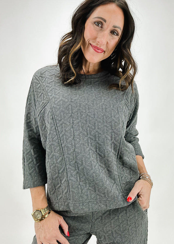 A woman wearing the Ivy Jane gray quilted long-sleeve top, paired with matching pants for a comfortable and stylish ensemble.