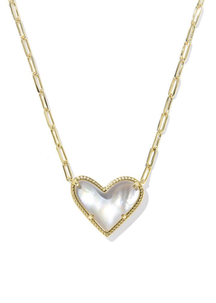 Gold necklace with an ivory, gold framed, and heart shaped pendant against a white background