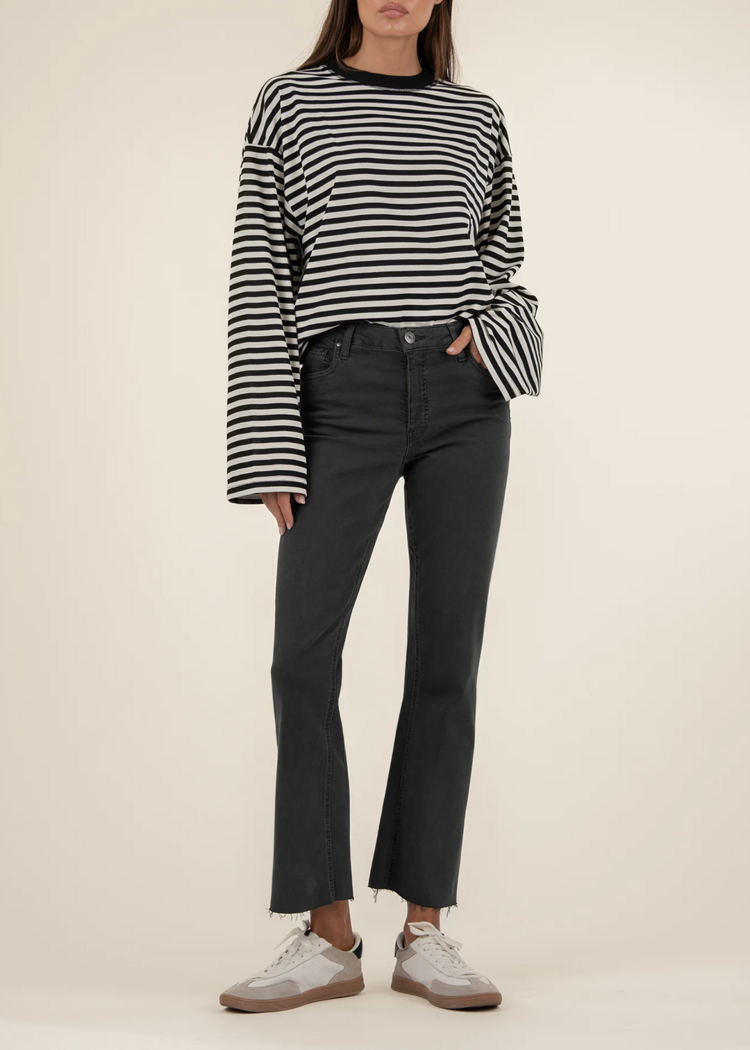 Woman wearing high rise ankle flare jeans in a dark pewter green color with a black and white striped top in front of a white background