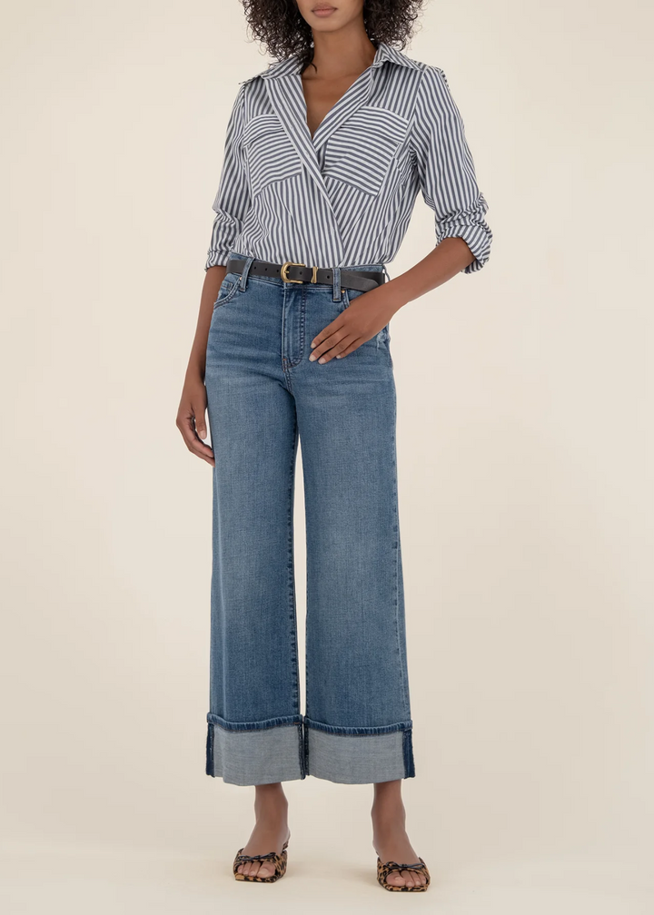 Woman wearing a medium wash denim rolled up jeans with a striped button down top