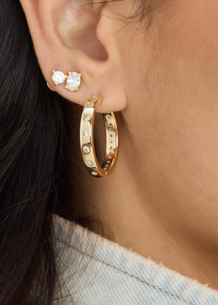 Woman wearing diamond studs earrings and a gold hoop with CZ studding