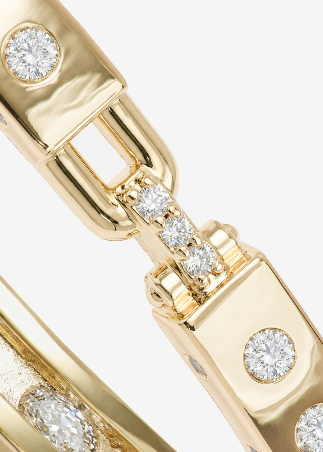 Close up of a gold cuff bracelet with CZ studding on a white background