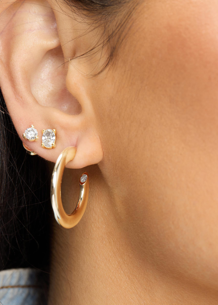 Woman wearing diamond studs and gold hoop earrings