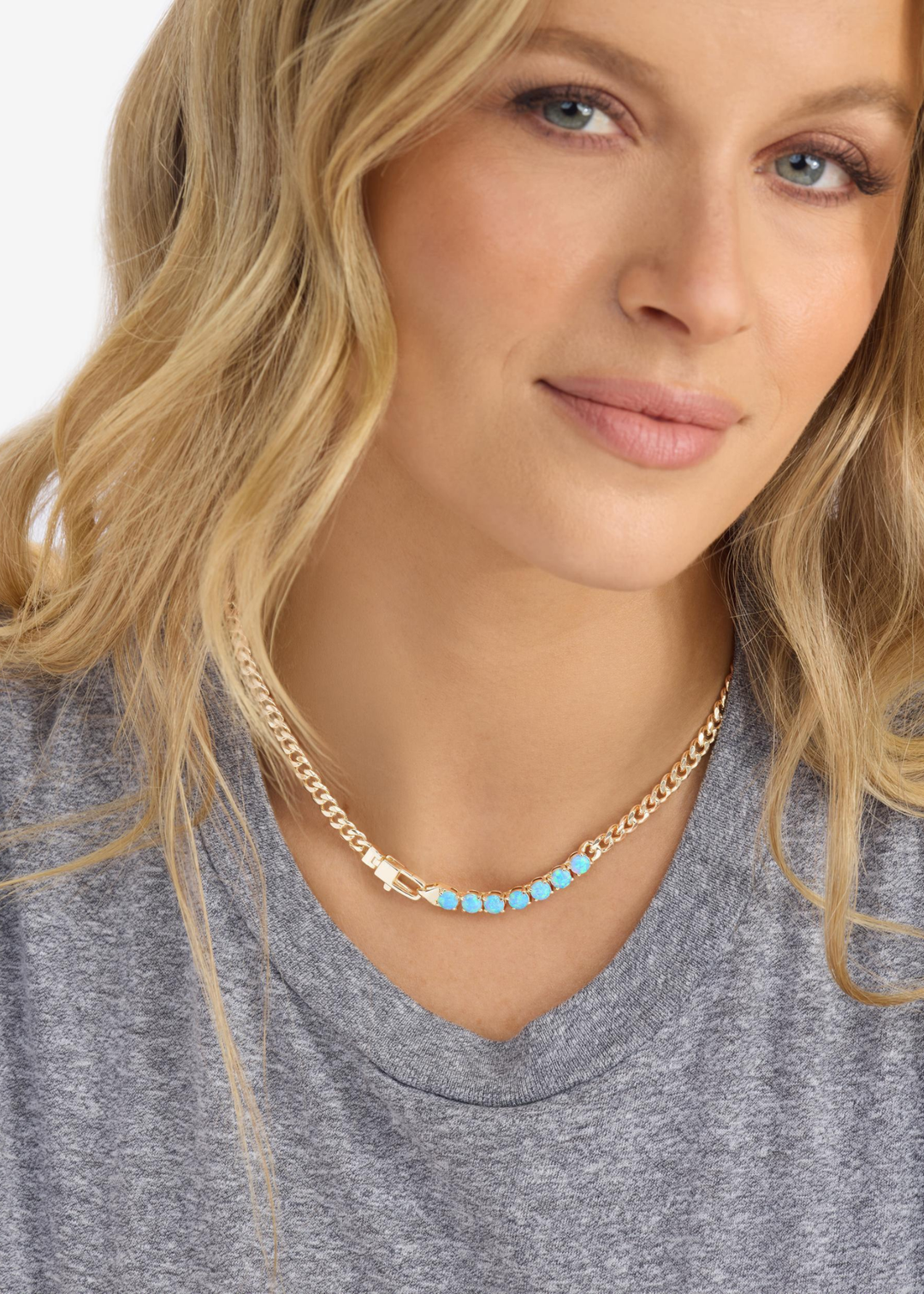 Woman wearing a gold chain necklace with seven blue opal stones